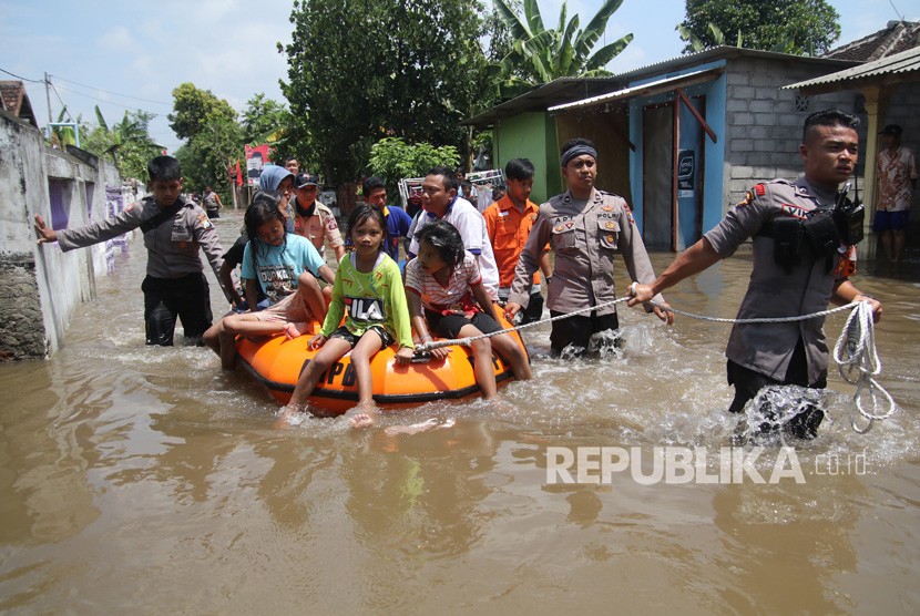 Petugas Badan Penanggulangan Bencana Daerah (BPBD) bersama anggota polisi mengevakuasi warga menggunakan perahu karet di kawasan yang terendam banjir. 
