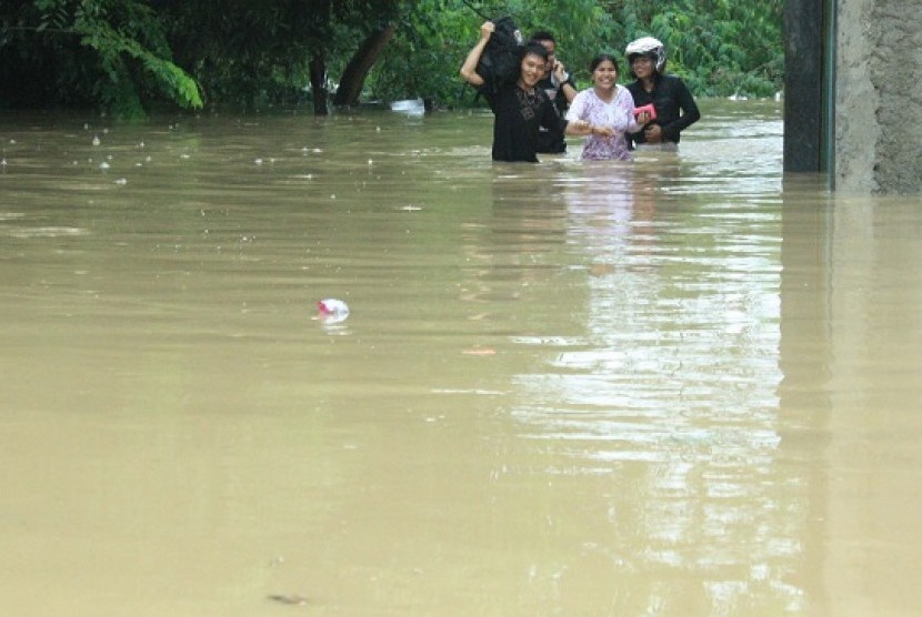 Warga membawa barang mereka melintasi banjir yang menggenangi Perumahan Bintang Alam, Telukjambe Timur, Karawang, Jabar.