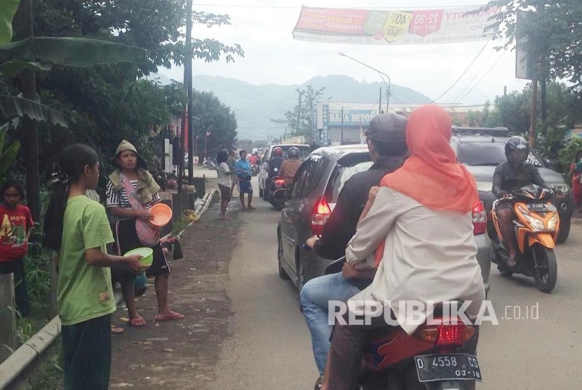 Seiring dengan banjir luapan Citarum, sejumlah orang meminta sumbangan di Jalan Bojongsoang, Kecamatan Dayeuhkolot, Kabupaten Bandung, Ahad (30/10). 