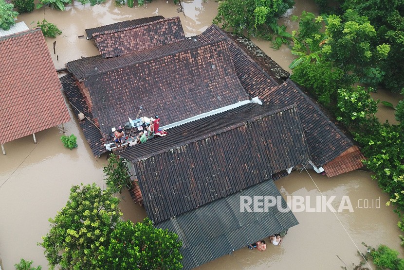Banjir Madiun. Sejumlah warga menyelamatkan diri di atas atap rumah saat terjadi banjir di Desa Purworejo, Pilangkenceng, Kabupaten Madiun, Jawa Timur, Rabu (6/3/2019).