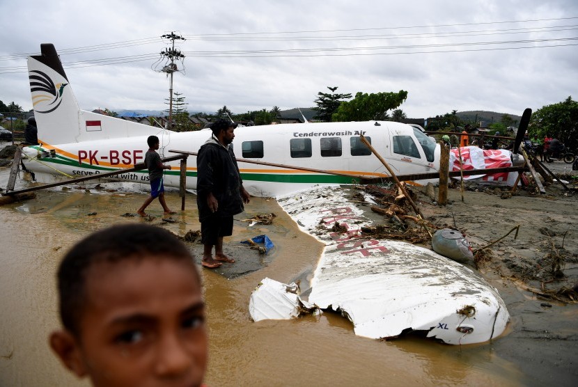 Banjir Sentani. Warga mengamati sebuah pesawat yang terseret banjir bandang di Sentani, Jaya Pura, Papua, Senin (18/3).