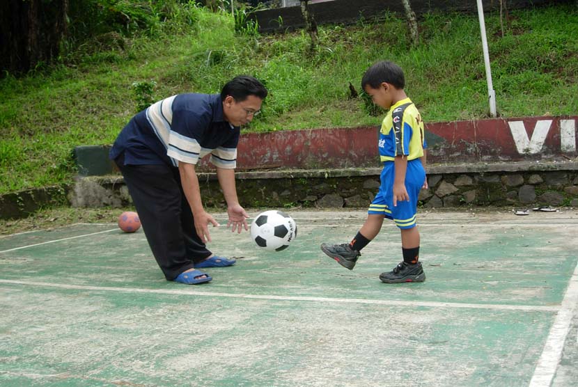 Ayah mengajari anaknya bermain bola di lapangan (ilustrasi). Fenomena fatherless dapat sangat memengaruhi ketahanan keluarga Indonesia.