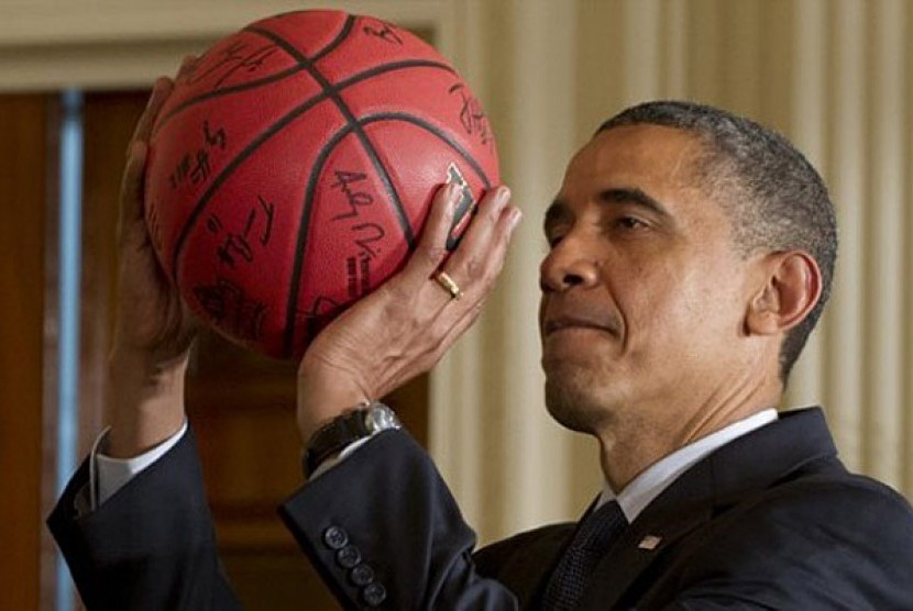 Barack Obama memegang bola basket. 