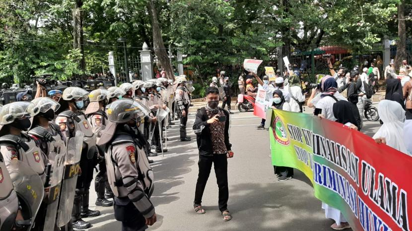 Barisan aparat hendak memukul mundur massa aksi 1812 di Jalan Merdeka Selatan, tepatnya  di depan kantor Kementerian BUMN, Jumat (18/12) pukul 13.50 WIB.