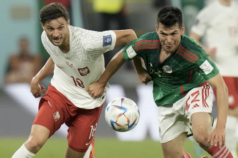 Bartosz Bereszynski dari Polandia, kiri, dan Hirving Lozano dari Meksiko bertarung memperebutkan bola selama pertandingan sepak bola grup C Piala Dunia antara Meksiko dan Polandia, di Stadion 974 di Doha, Qatar, Selasa, 22 November 2022. 
