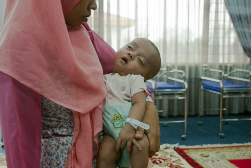 Bayi berusia empat bulan bernama Gibran digendong oleh ibunya di Posko Evakuasi Korban Asap di Kantor Wali Kota Pekanbaru, Riau, Rabu (30/9).