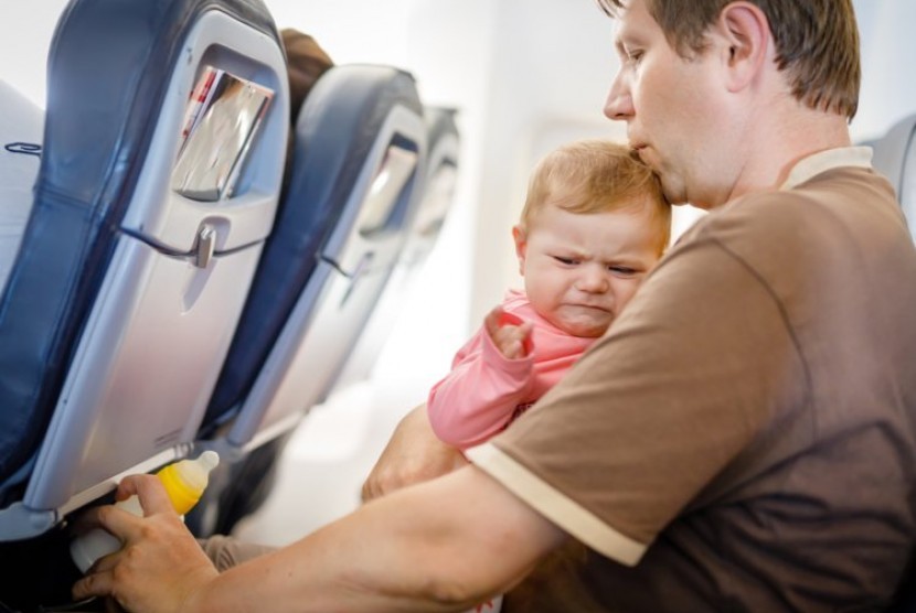 Bayi menangis di pesawat. Konsultasikan dengan dokter anak sebelum mengajak bayi melakukan perjalanan dengan pesawat.