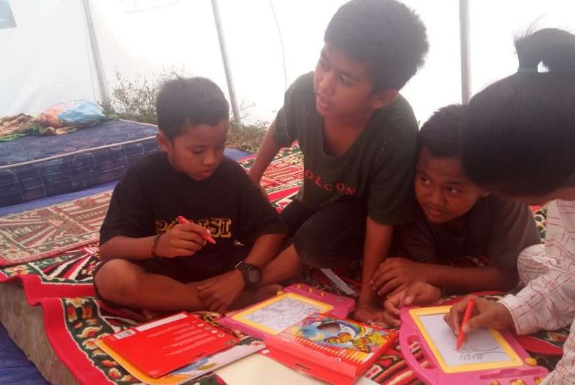 Beberapa anak tengah asyik menggambar di dalam kelas darurat yang didirikan Kemendikbud. Kelas darurat didirikan di camp pengungsian Petobo, Kota Palu.