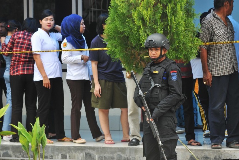 Beberapa anggota Polisi bersenjata lengkap tengah berjaga di depan Ruangan Instalasi Forensik RS Bhayangkara, Palu, Sulawesi Tengah, Selasa (19/7). 