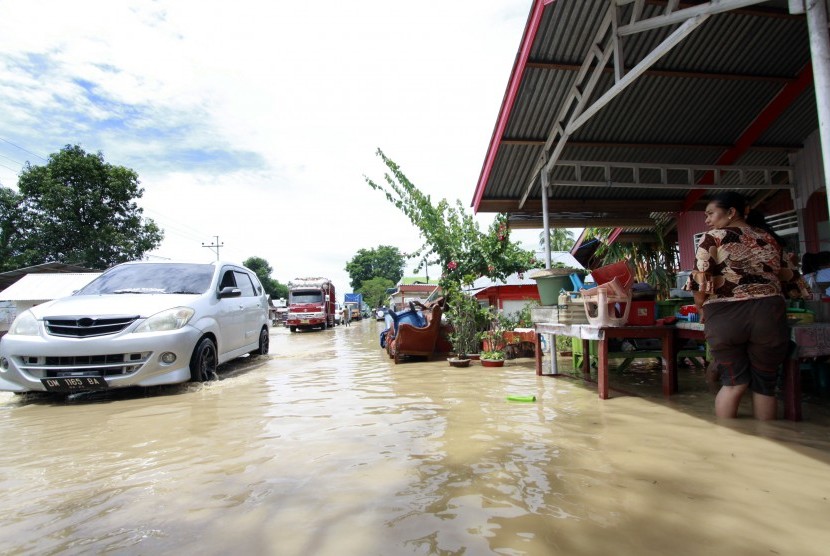 Beberapa kendaraan melaju melewati banjir di jalan Trans Sulawesi, Limboto, Kabupaten Gorontalo, Rabu (26/10). 