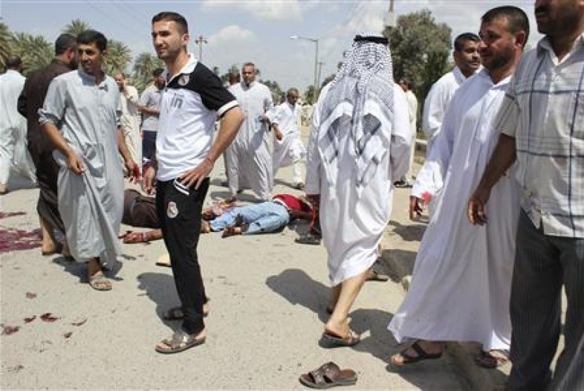 Beberapa orang berkumpul di lokasi pengeboman di Baqua, 50 kilometer utara Baghdad