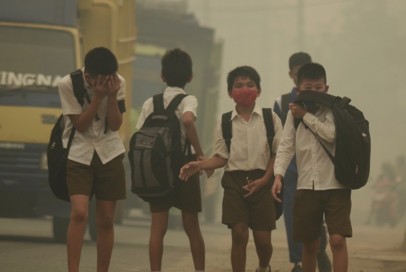   Beberapa pelajar SMP 15 Kota Jambi berjalan pulang menembus kabut asap dari sekolah di Jalan Lingkar Timur, Jambi, Selasa (29/9).
