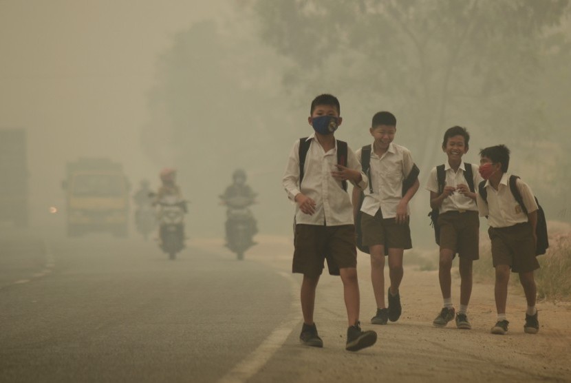 Beberapa pelajar SMP 15 Kota Jambi berjalan pulang menembus kabut asap dari sekolah di Jalan Lingkar Timur, Jambi, Selasa (29/9). 