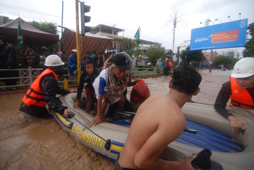   Beberapa petugas Palang Merah Indonesia (PMI) Sulut menggunakan perahu karet ketika membantu warga menyeberangai banjir di Kelurahan Wenang, Manado, Sulawesi Utara, Rabu (15/1).   (Antara/Fiqman Sunandar)