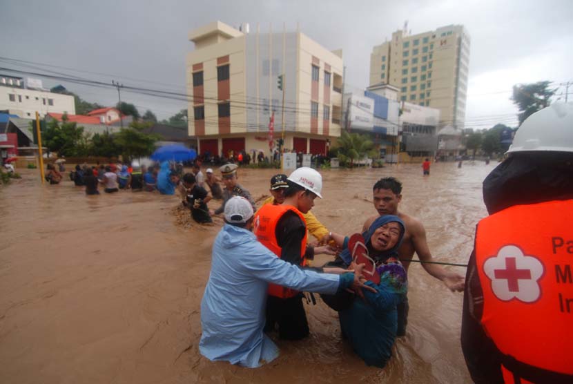  Beberapa petugas Palang Merah Indonesia (PMI) Sulut membantu warga menyeberangai banjir di Kelurahan Wenang, Manado, Sulawesi Utara, Rabu (15/1).
