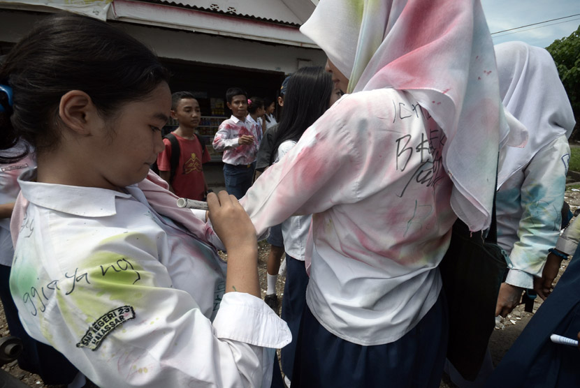 Beberapa siswa SMP saling membubuhkan tanda tangan di seragam usai pelaksanaan hari terakhir Ujian Nasional (UN), Makassar, Sulawesi Selatan, Kamis (7/5). (ANTARA/Dewi Fajriani)