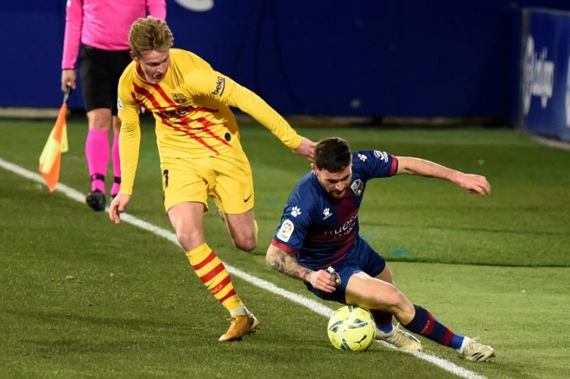 Bek Huesca Javi galan (kanan) berebut bola dengan gelandang Barcelona Frenkie De Jong dalam pertandingan La Liga Spanyol, Senin (4/1) dini hari WIB. De Jong mencetak gol kemenangan Barcelona 1-0. 