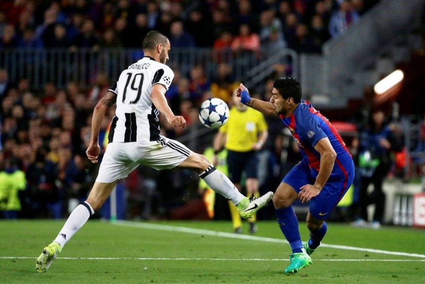 Bek Juventus Leonardo Bonucci (kiri) saat menahan upaya serangan penyerang Barcelona Luis Suarez.