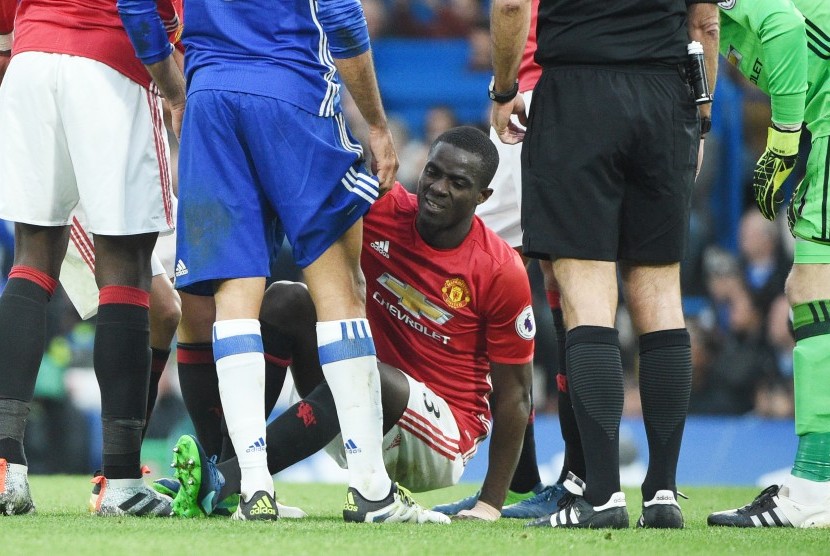 Bek Manchester United, Eric Bailly dibantu berdiri setelah terjatuh pada laga Liga Primer lawan Chelsea di Stamford Bridge, Ahad (23/10). Pascalaga itu, Bailly didiagnosis menderita cedera otot ligamen lutut.