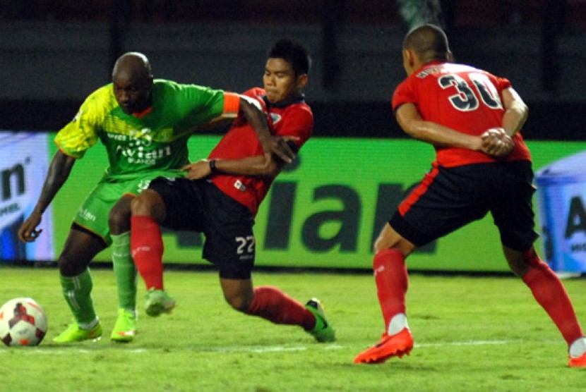 Bek Pelita Bandung Raya Wildansyah (tengah) berusaha mengadang laju pemain Persebaya Emanuel Kenmogne, Ahad (26/10).