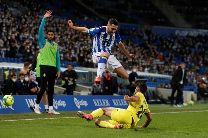 Bek Real Sociedad, Joseba Zaldua melompat menghindari tekel dari gelandang Villarreal, Alfonso Pedraza pada laga La Liga, Sabtu (18/12). Villarreal menang 3-1.