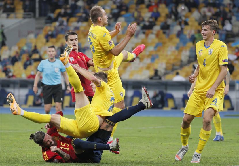 Bek sekaligus kapten timnas Spanyol, Sergio Ramios (bawah), terjatuh ketika berduel dengan pemain Ukraina Eduard Sobol (tengah) dan lllia Zabarnyi (kanan) saat kedua tim bentrok pada lanjutan Liga Bangsa-Bangsa, Rabu (14/10).
