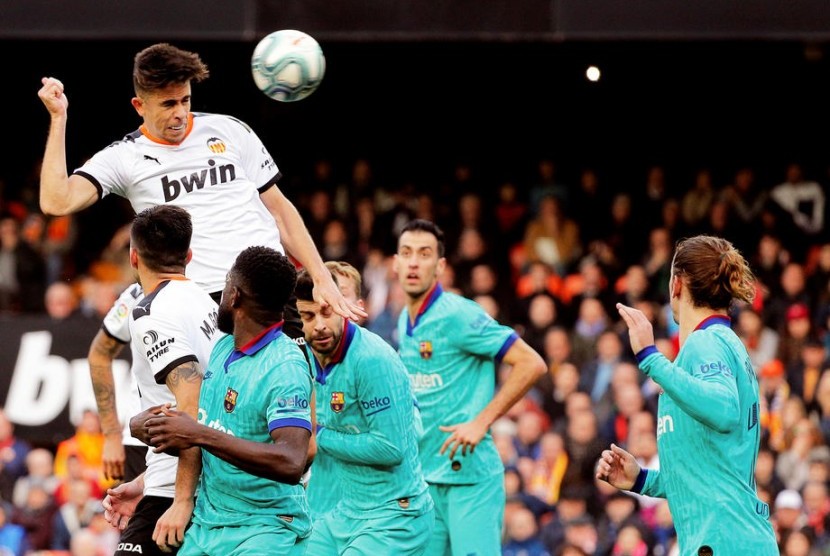 Bek Valencia, Gabriel Paulista (tengah) menyundul bola di antara kawalan pemain Barcelona pada laga La Liga di Stadion Mestalla, Sabtu (25/1). Valencia menang 2-0.