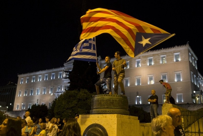 Bendera Estelada atau kelompok separatis Katalonia dan bendera Yunani dikibarkan depan gedung parlemen di Athena (29/6). Masyarakat Yunani terkena dampak krisis yang berkepanjangan mengakibatkan penutupan bank dan antrian panjang di supermarket.
