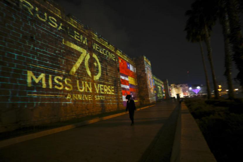 Bendera negara-negara yang berpartisipasi di kontes kecantikan Miss Universe diproyeksikan ke dinding di Kota Tua Yerusalem, 30 November 2021. Salah seorang kontestan Miss Universe menjalani isolasi terpusat di hotel setelah dites positif Covid-19. 