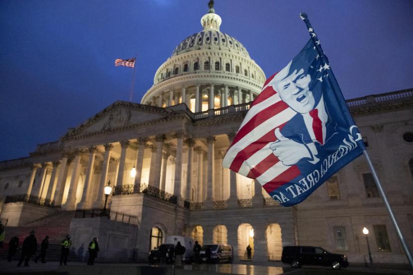 Bendera pendukung Donald Trump dikibarkan pendukungnya saat massa menyerbu Capitol Hill pada Rabu (6/1).