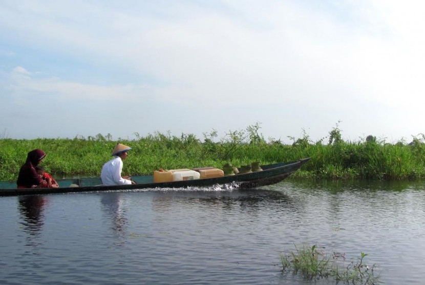 Bersama suami dan anak, perempuan di Daha Selatan sering bolak-balik ke kebun naik perahu kelotok sekitar satu jam perjalanan.