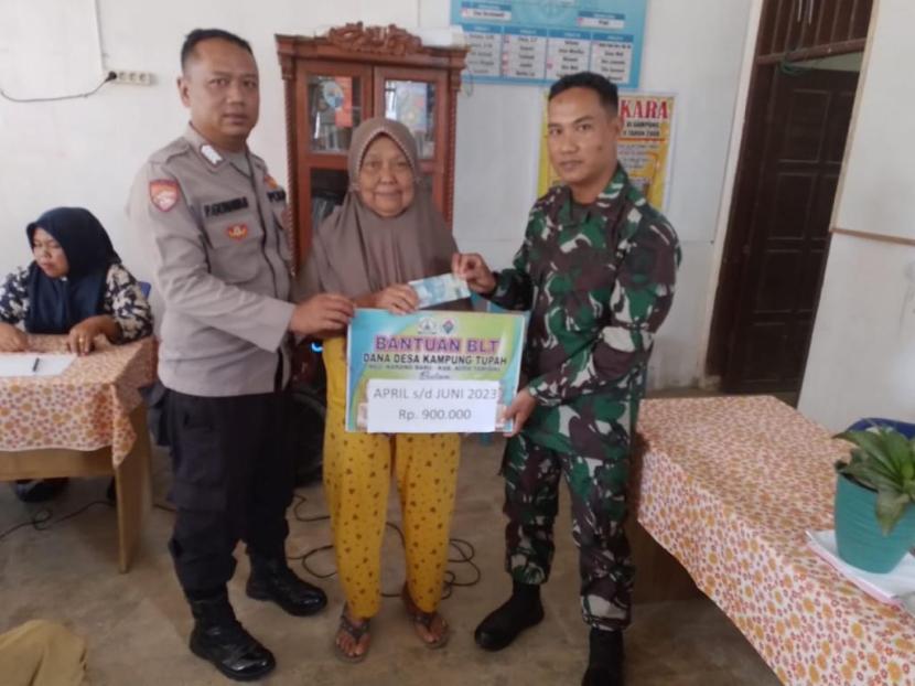 Bhabinkamtibmas Desa Bundar Bripka Fadjar Gunawan dan Babinsa Serda Dadang Firman memantau pembagian BLT di Aceh Tamiang, Selasa (15/8/2023).
