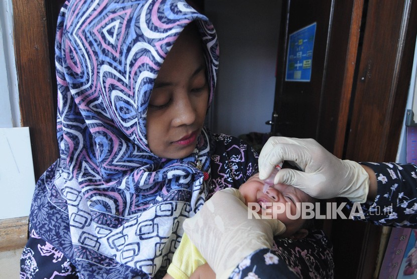 Dinkes Imbau Masyarakat Tetap Imunisasi Anak. Bidan (kanan) memberikan imunisasi polio pada bayi usia dua bulan di Pamekasan, Jawa Timur.