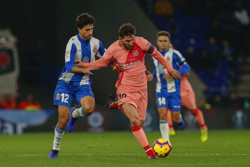 Bintang Barcelona Lionel Messi (tengah) melewati adangan pemain Espanyol.