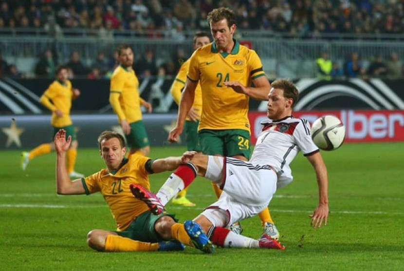  Bintang Jerman Benedikt Hoewedes ditackle oleh Alex Wilkinson (22) dari Australia.