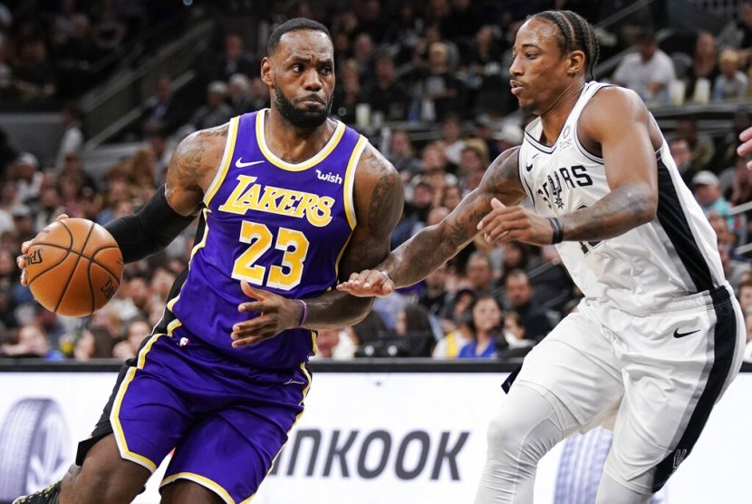 Bintang Los Angeles Lakers LeBron James (kiri) berusaha melewati pemain San Antonio Spurs DeMar DeRozan.
