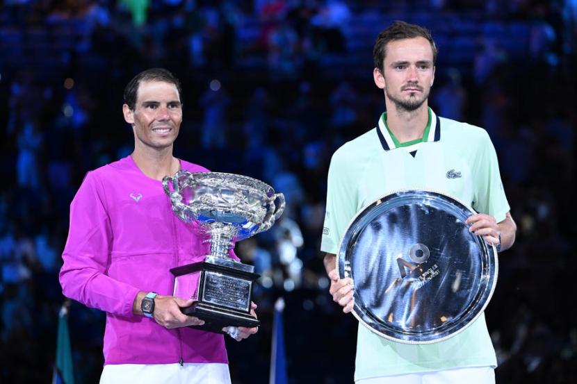 Bintang tenis Spanyol Rafael Nadal (kanan) memegang Norman Brookes Challenge Cup setelah menaklukkan Daniil Medvedev dari Rusia di final tunggal putra Australian Open, Ahad (30/1/2022).