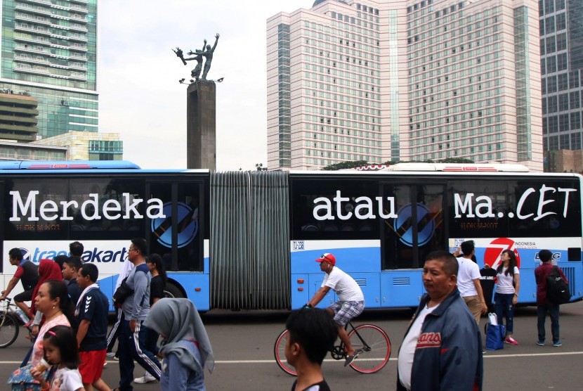 Bis TransJakarta yang bertuliskan Merdeka Atau Macet melintasi area Car Free Day di kawasan Bundaran HI, Jakarta, Minggu (14/8). 