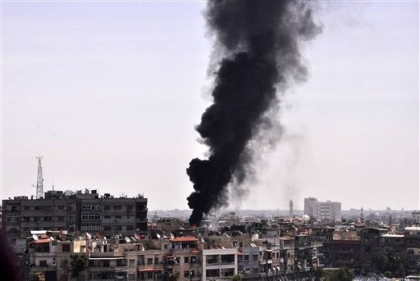 Black smoke rises from the rooftop of a building that was, according to SANA, attacked by a mortar shelled by the Syrian rebels in Damascus, Syria, Saturday, April 5, 2014.