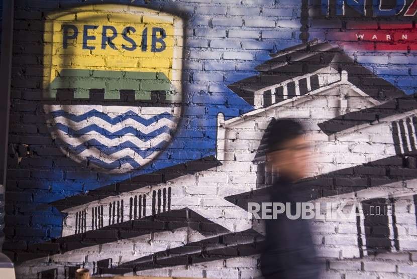 Bobotoh alias pendukung Persib berjalan di depan mural Persib di Bandung, Jawa Barat, Selasa (2/10). 