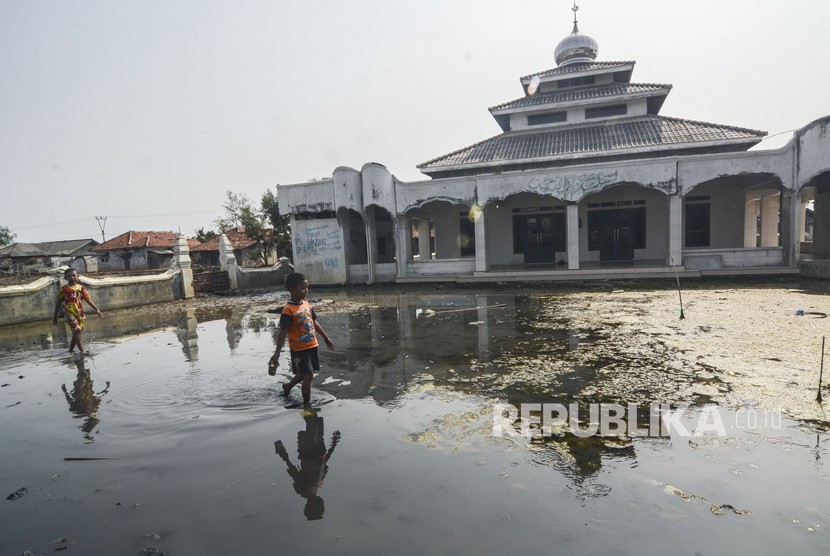 Bocah bermain di halaman Masjid yang tergenang banjir rob di Desa Pantai Bahagia, Muaragembong, Kabupaten Bekasi, Jawa Barat, Selasa (6/8/2019). 