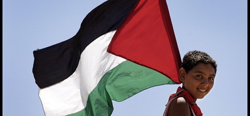 Bocah Palestina mengibarkan bendera negaranya.