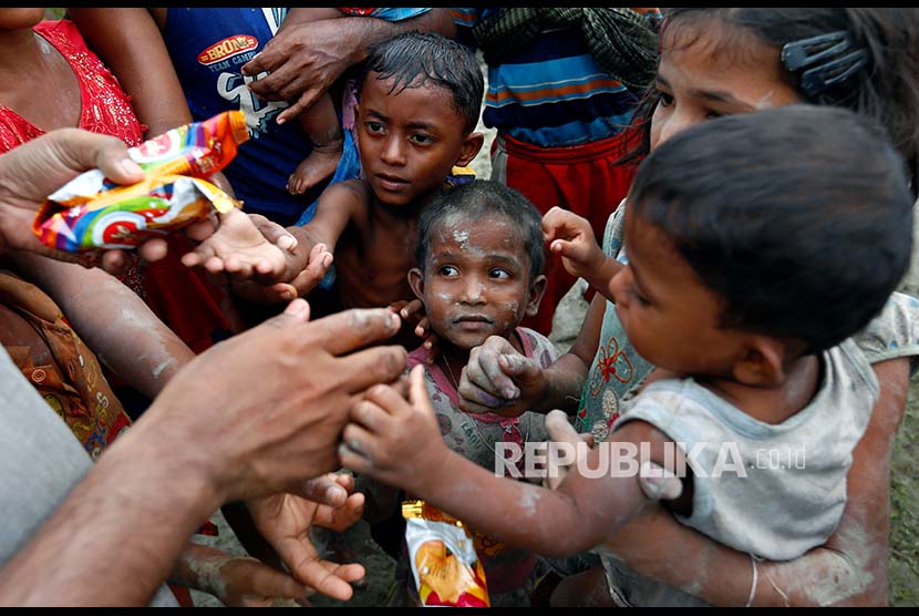 Bocah pengungsi Rohingya berbagi makanan setelah melintasi pesawahan setelah melintasi perbatasan Bangladesh-Myanmar di Teknaf, Bangladesh, Rabu (6/9).