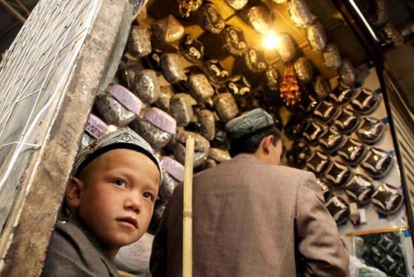 Bocah Uighur saat membantu ayahnya berjualan kopiah di Kota Urumqi, Xinjiang.