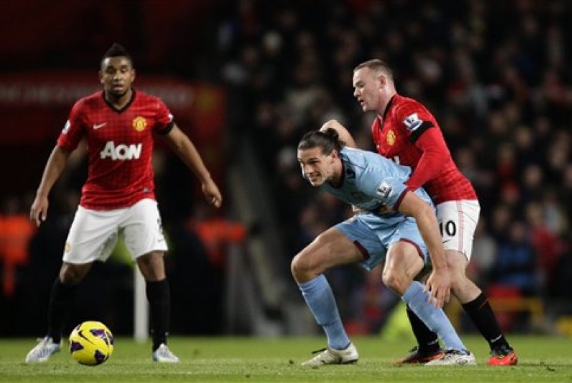 Bomber Manchester United (MU), Wayne Rooney, menjaga penyerang West Ham, Andy Carroll, sambil disaksikan gelandang MU, Anderson, pada laga di Old Trafford, Kamis (29/11) dini hari. MU menang 1-0 dan kokoh di puncak klasemen Liga Primer Inggris. 