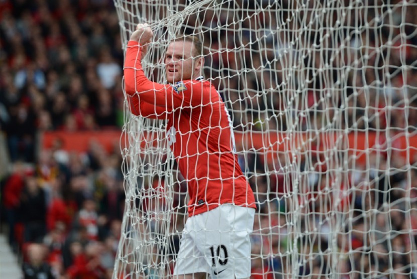 Bomber Manchester United Wayne Rooney memegang jaring gol saat laga melawan Swansea di Stadion Old Trafford, Manchester, Inggris, Minggu (6/5). Meski menang 2-0, MU masih tertinggal 8 gol dari rival sekota Manchester City.