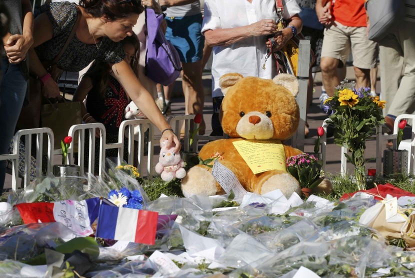 Boneka, bunga, dan bendera Prancis diletakkan di tepi jalan sebagai penghormatan atas korban di insiden truk Nice, Prancis.