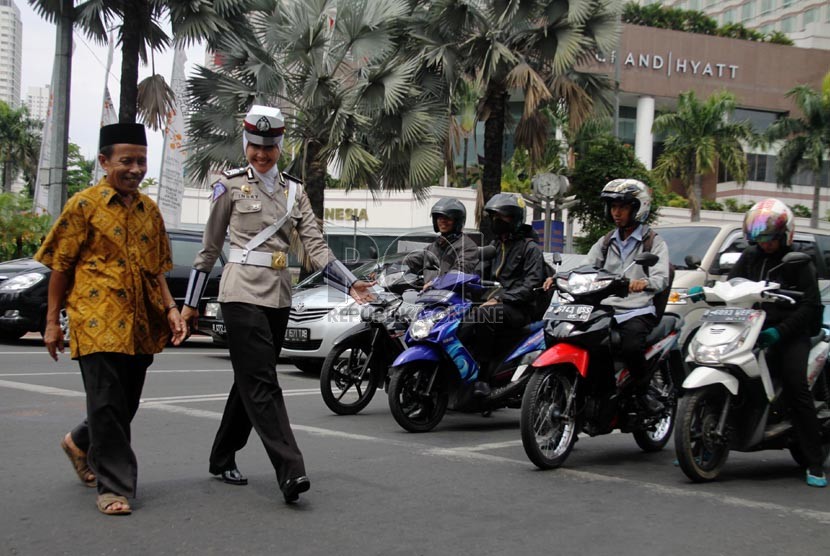   Bripka Novi dengan mengenakan seragam polisi berjilbab membantu warga menyeberang jalan di Bundaran HI, Jakarta Pusat, Senin (25/11).  (Republika/Yasin Habibi)