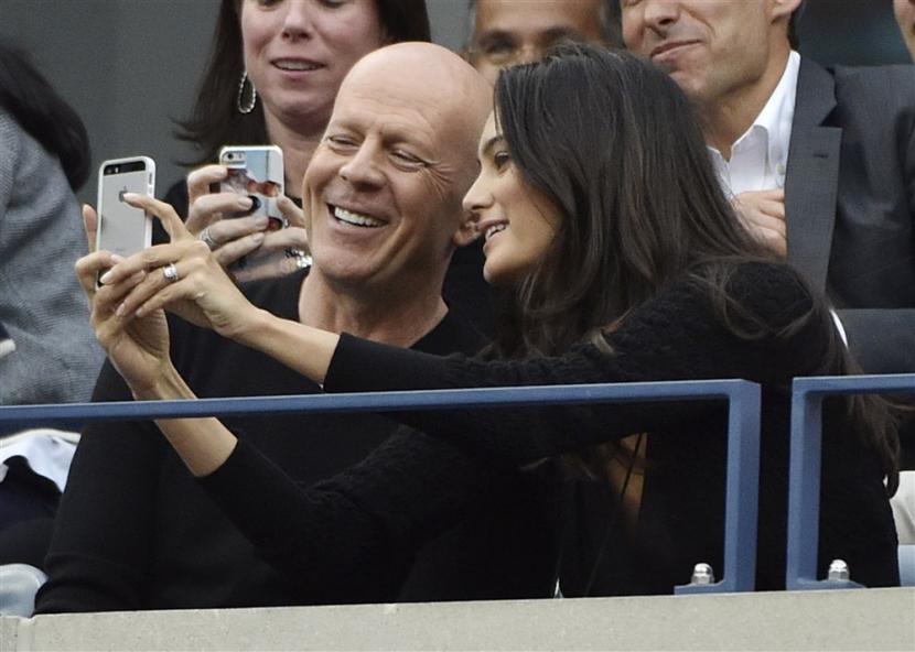 Bruce Willis (kiri) dan istrinya Emma Heming berfoto bersama saat menonton AS Terbuka 2014, di USTA National Tennis Center, Flushing Meadows, New York, Amerika Serikat, 8 September 2014. Willis kini menderita demensia frontotemporal.