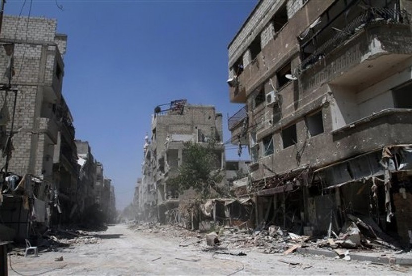 Buildings damaged during battles between Syrian troops and rebels stand along an empty street in Mleiha, some 10 kilometers (6 miles) southeast of downtown Damascus, Syria, Friday, Aug. 15, 2014. 